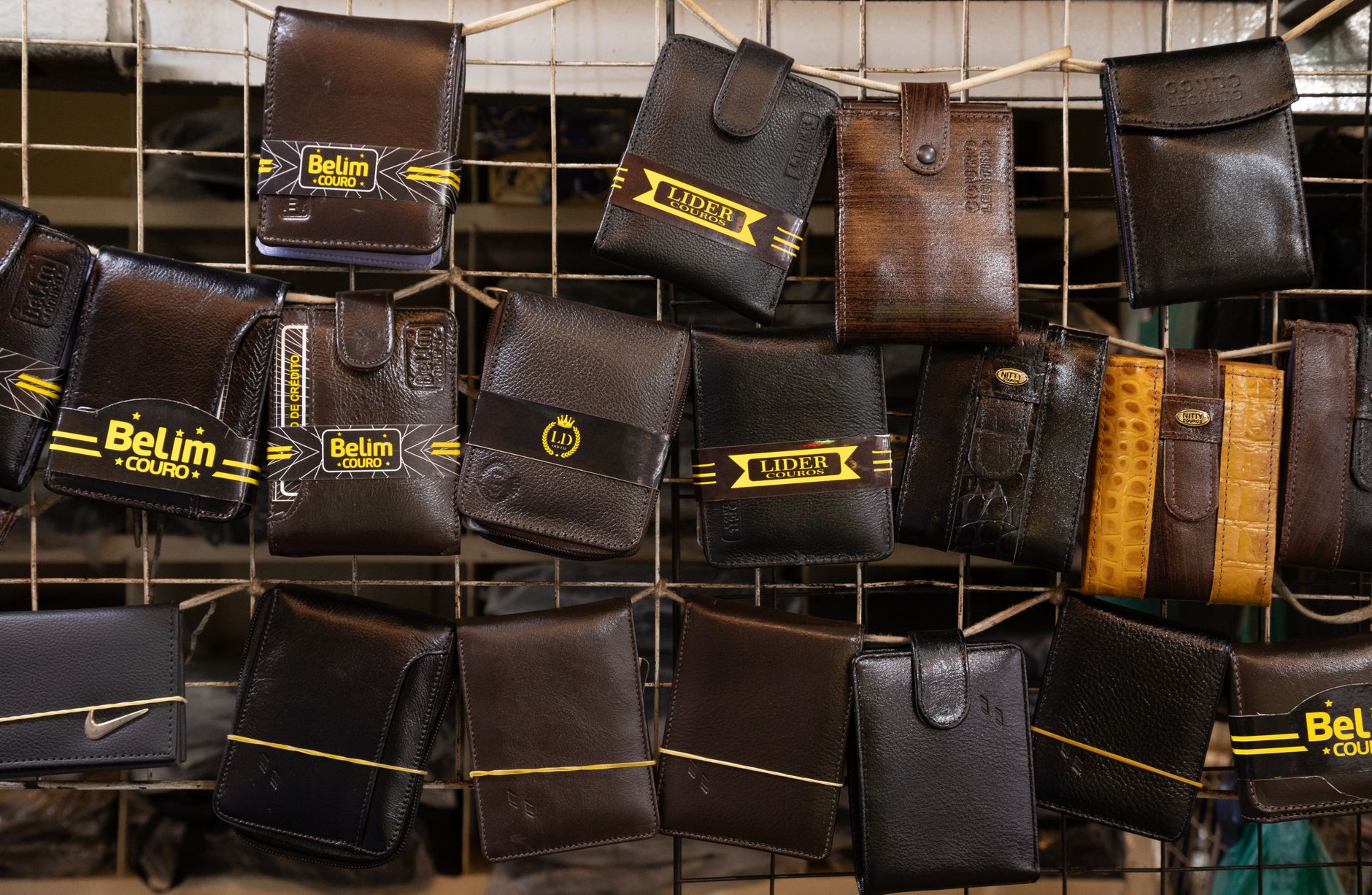 Collection of leather wallets on a market rack, showcasing diverse designs and finishes.