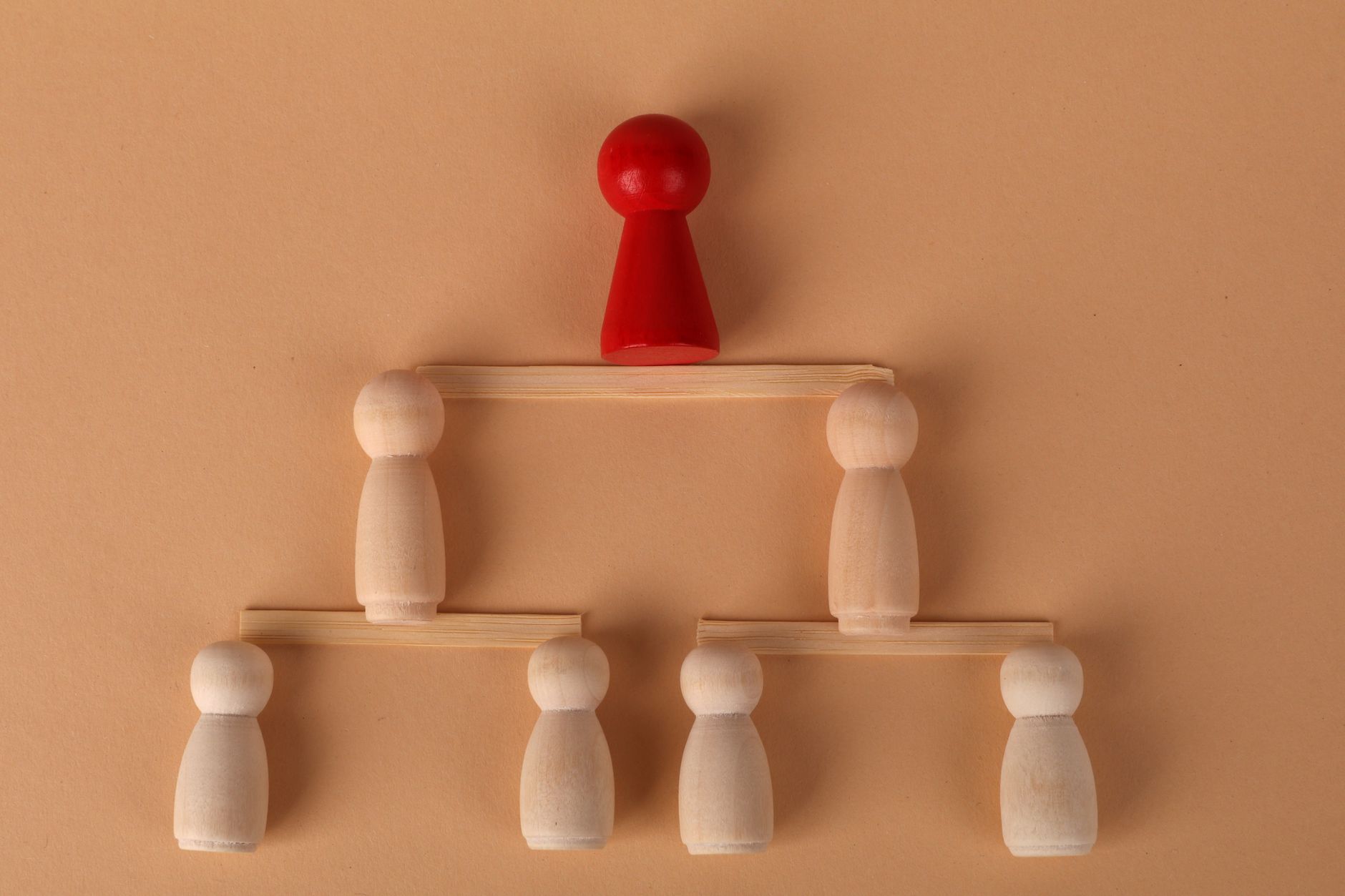 Wooden figures arranged to illustrate a hierarchical structure, symbolizing leadership and teamwork.