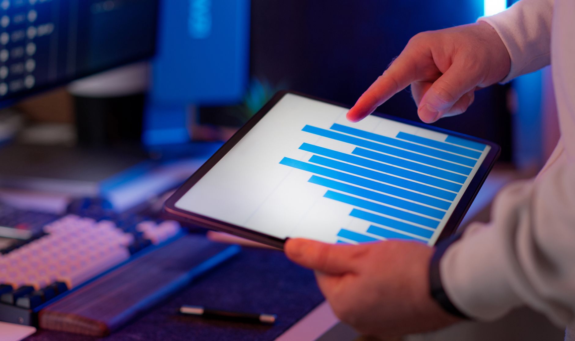 Business professional analyzing bar chart on tablet in office setting, highlighting data insights.