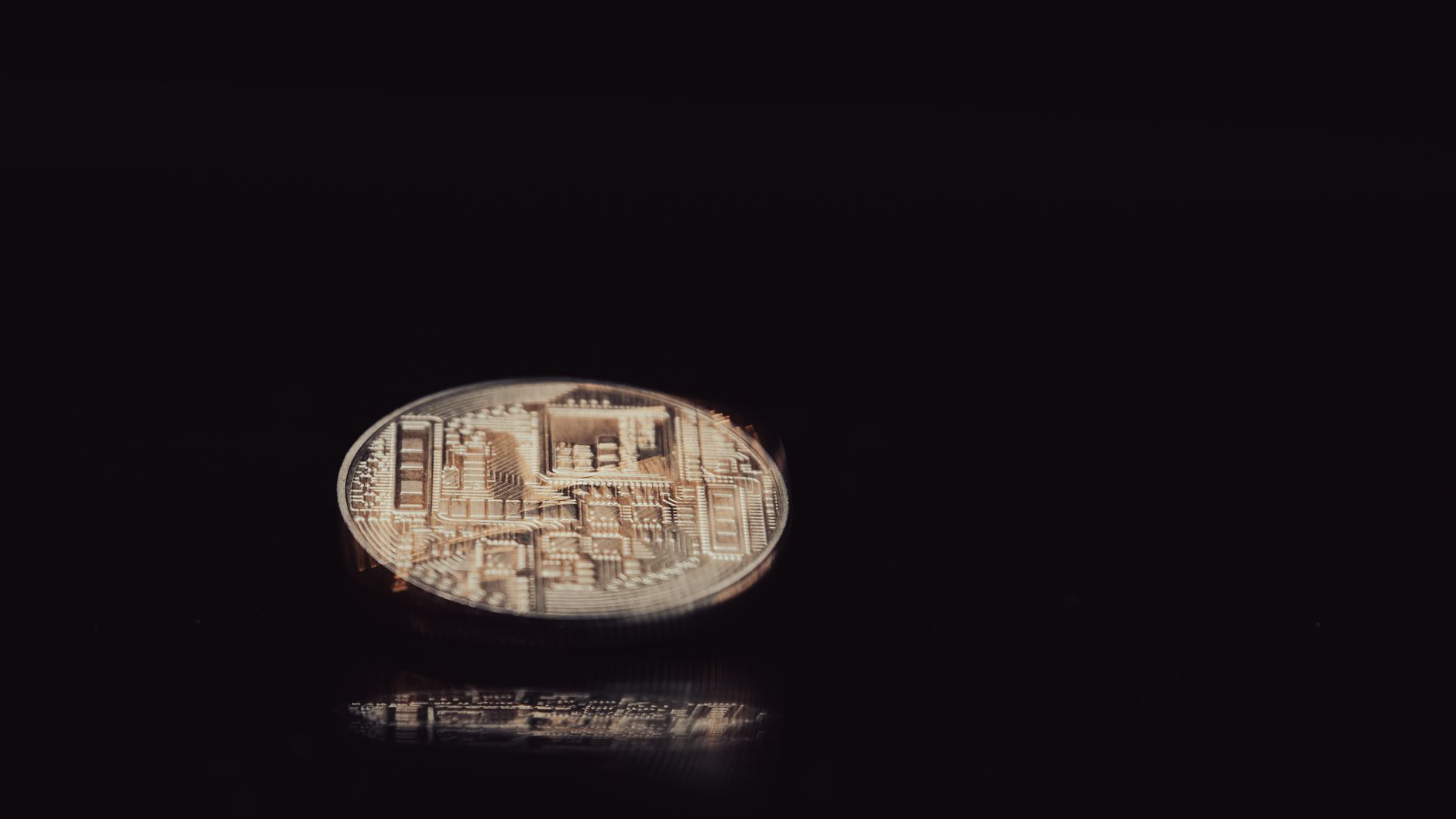 Detailed close-up of a digital cryptocurrency coin reflecting light on a sleek black background.